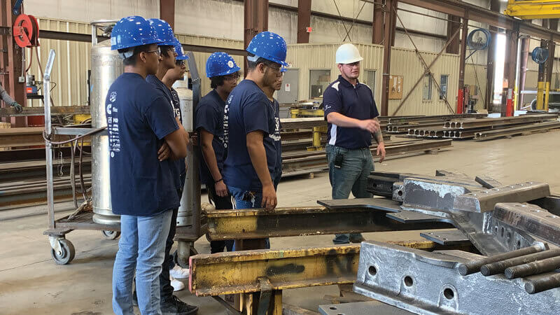 Tour of factory setting, people in hardhats