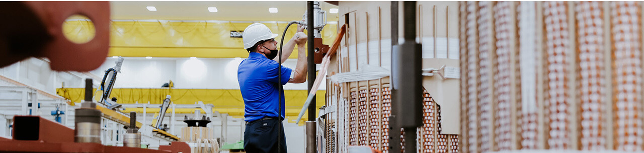Wide shot of man working inside with hard hat on ladder